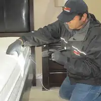 Bed bug inspection technician checking a mattress and bed frame for signs of infestation in Chicago, IL