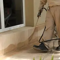 General pest control technician spraying exterior perimeter around a home in Chicago, IL
