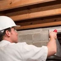 Termite inspection technician checking a basement wall and framing for termite activity in Chicago, IL